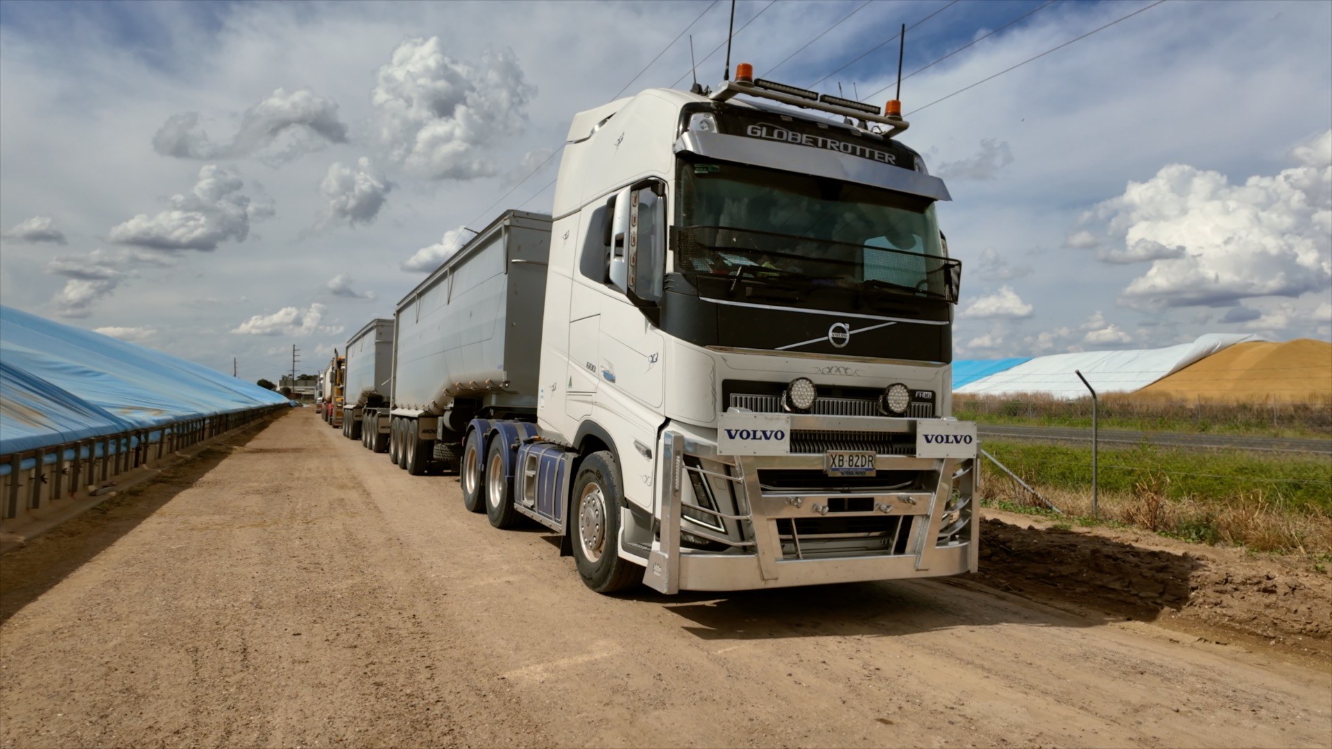 Volvo prime mover with a road train of grain tippers on a dirt road